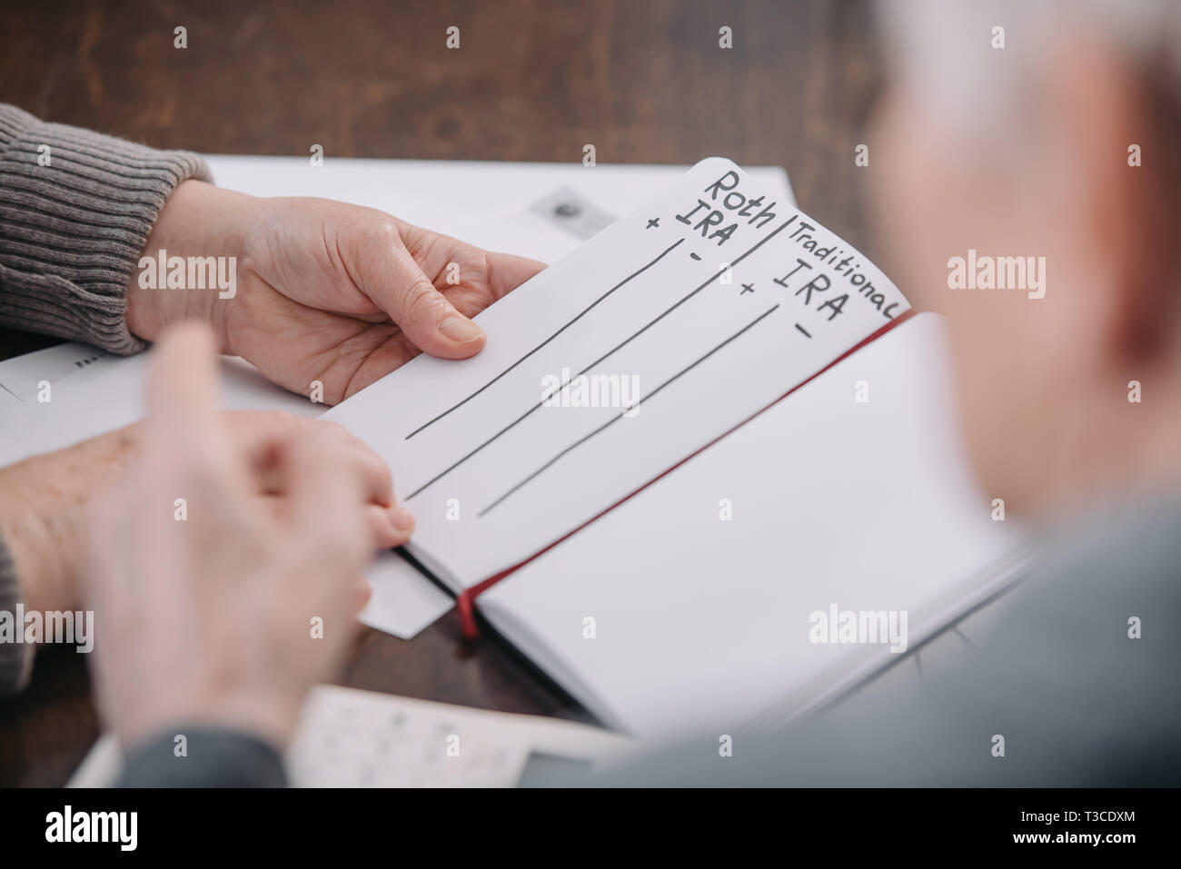 senior couple holding notebook with roth ira and traditional ira words Stock Photo