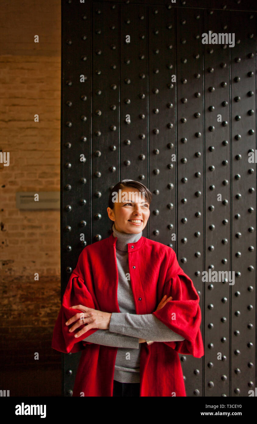 Smiling young woman stands in front of a studded iron door Stock Photo ...