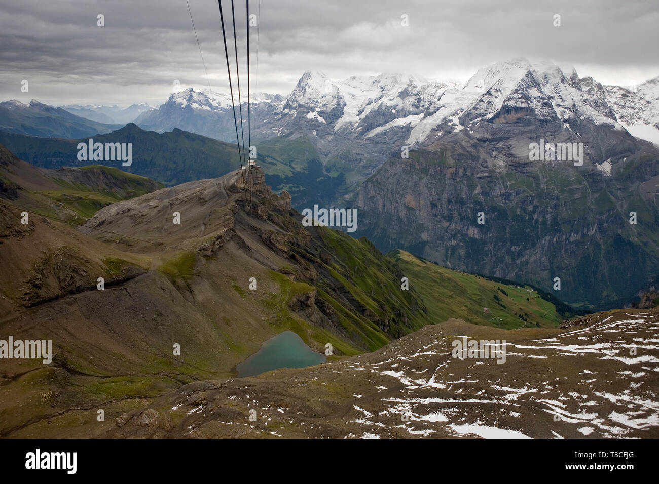The Birg cablecar station perched above a cliff with the Jungfrau Massif and the Lauterbrunnen valley beyond and the Grauseeli, a small mountain tarn, Stock Photo