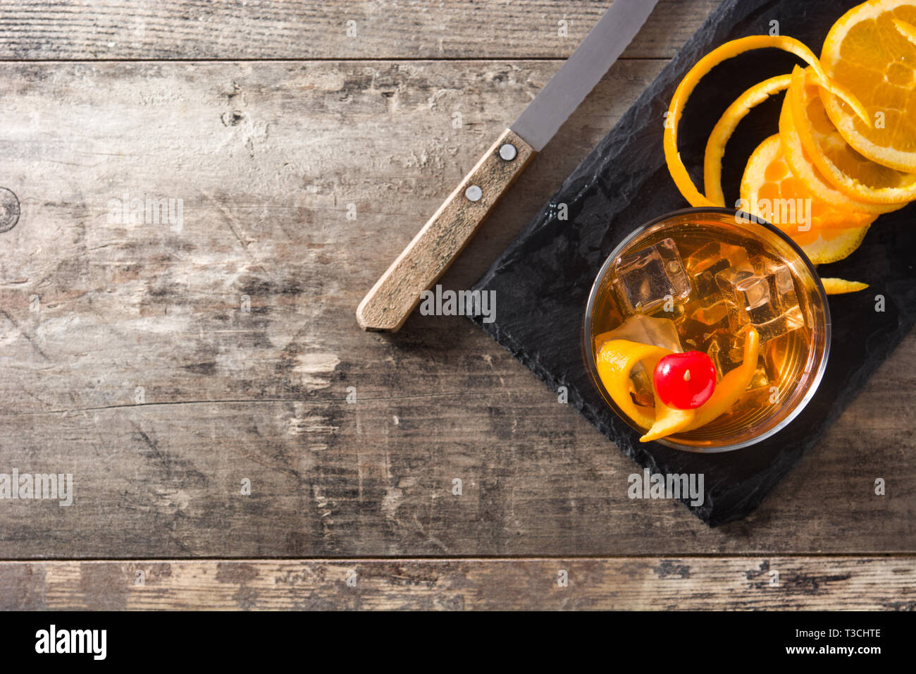 Old fashioned cocktail with orange and cherry on wooden table. Top view ...