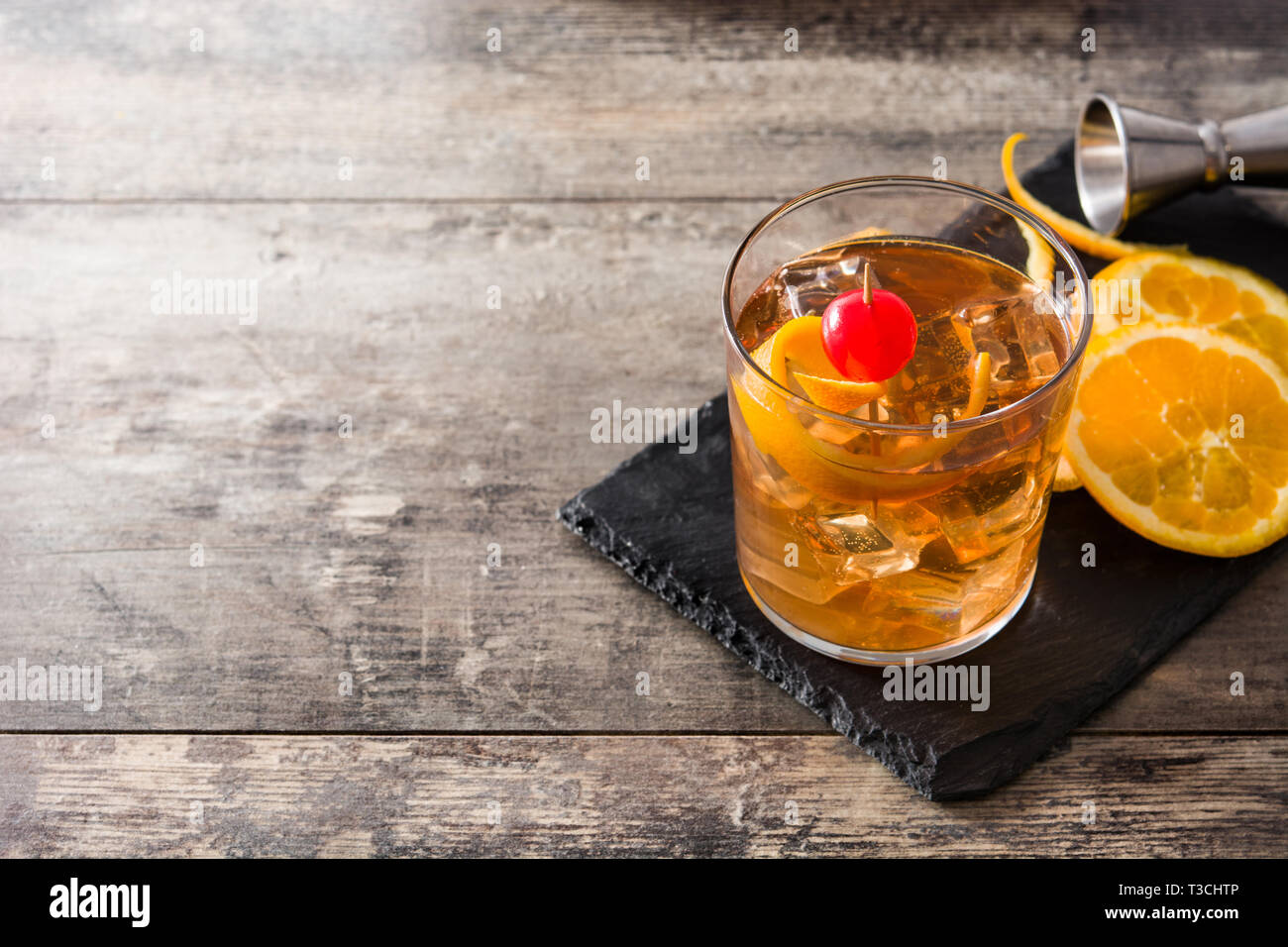 Old fashioned cocktail with orange and cherry on wooden table ...