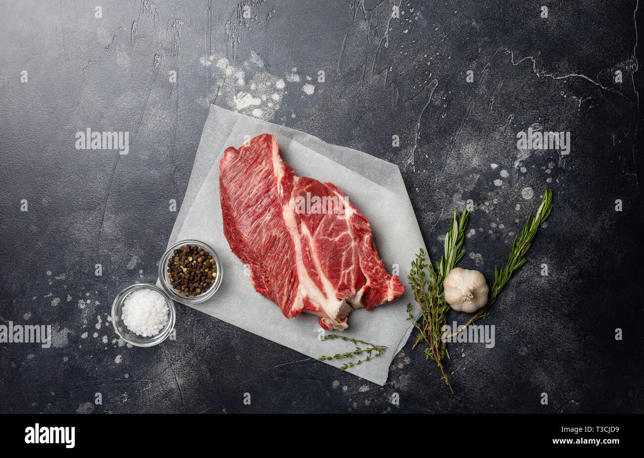 Fresh piece of red beef meat on gray background with herbs, salt and pepper. Vertical, copy space for text. Top view. Concept of fresh food Stock Photo
