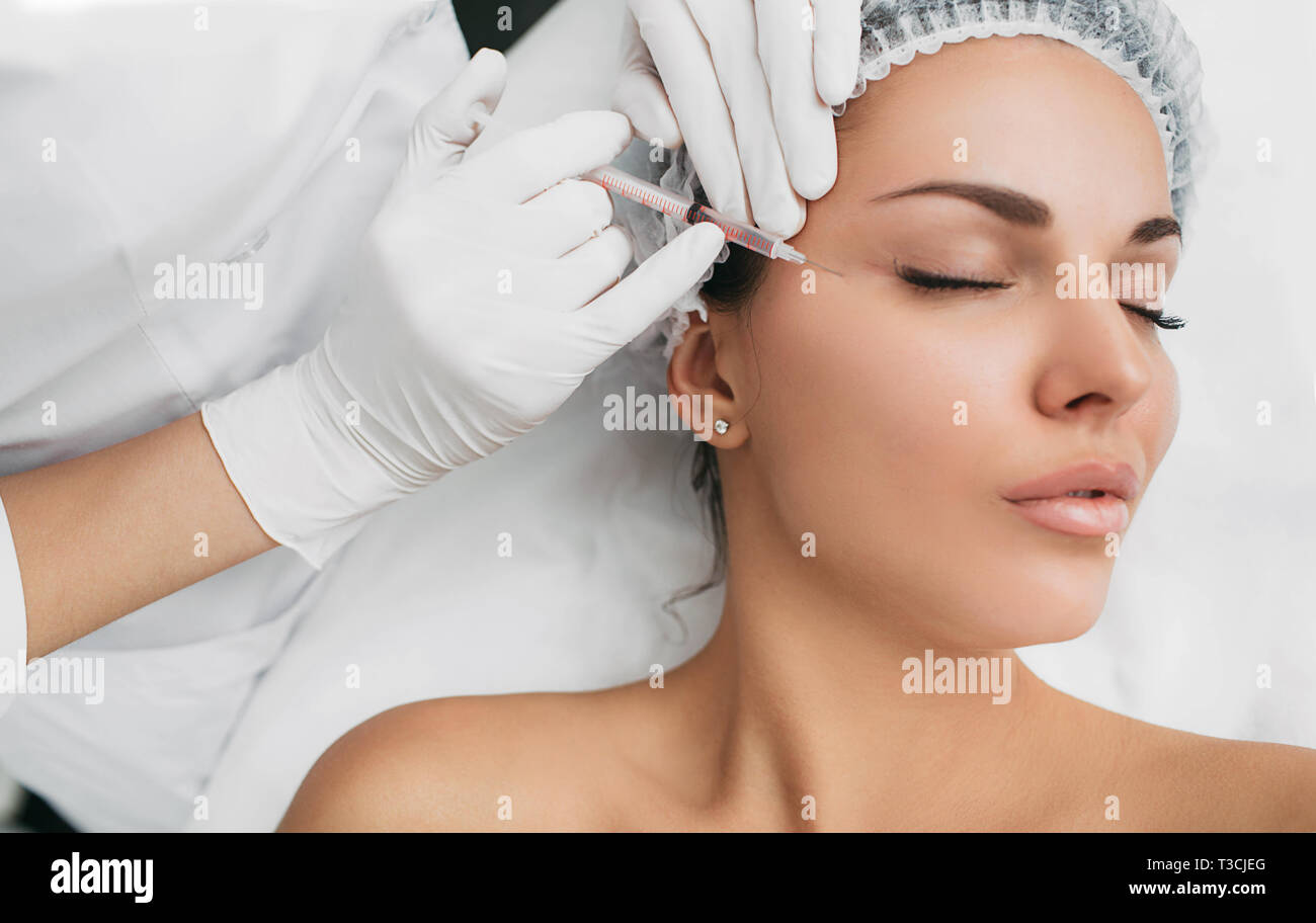 woman receiving injection on face, removing facial wrinkles around the eyes Stock Photo