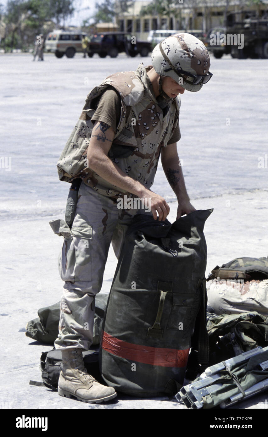 30th October 1993 U.S. Army soldier, Private Robinson of the 24th Infantry Division, checks his kit bag with other pieces of kit scattered around his feet after having just arrived by ship in Mogadishu's new port, Somalia. Stock Photo