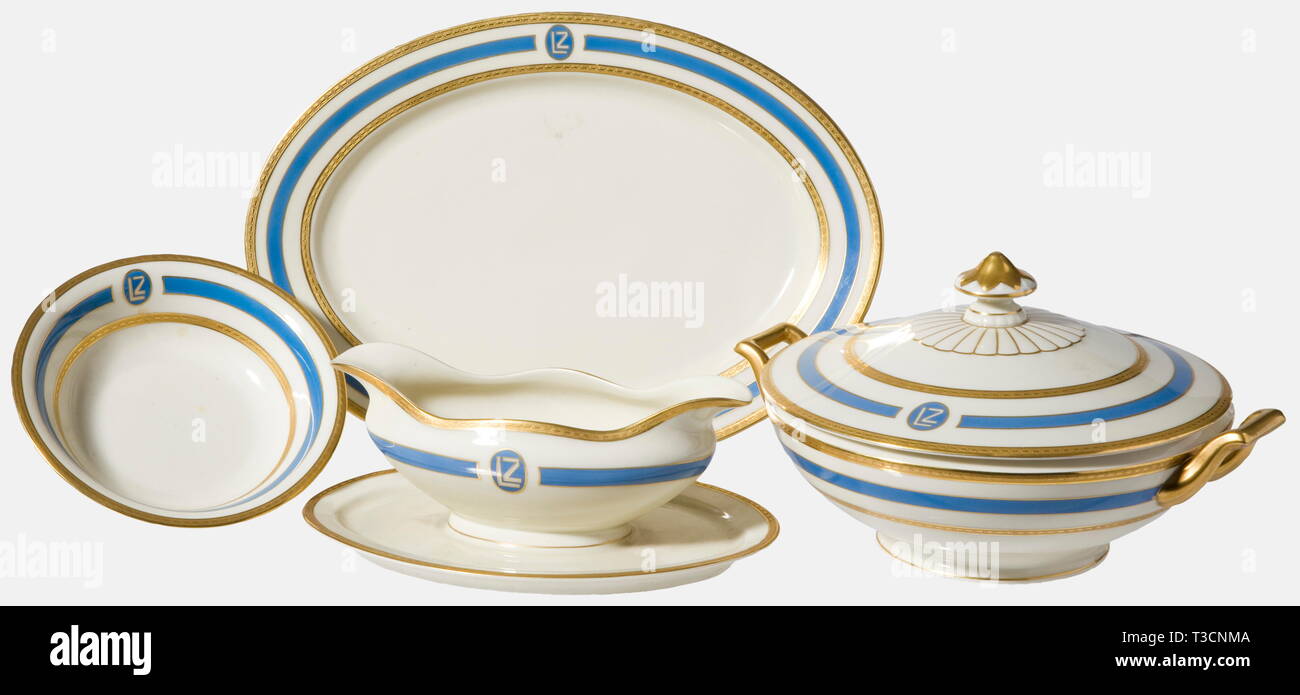 Four service pieces, from the on-board service of the LZ 127 'Graf Zeppelin', 1928 Heinrich & Co., Selb. Ivory coloured glazed porcelain with double blue and gold etched border décor and an vertically oval 'LZ' cartouche, On the bottom the underglaze green manufactory's mark with legend in red 'Heinrich-Elfenbein-Porzellan' and 'Graf Zeppelin 1928'. Consisting of a covered tureen with handles (height 14.5, diameter 22.5 cm), sauce boat (ca. 23.5 x 15.5 x 9 cm), oval service plate (32.5 x 23.5 cm), and a small bowl (height 4 cm, diameter 16.5 cm)., Additional-Rights-Clearance-Info-Not-Available Stock Photo