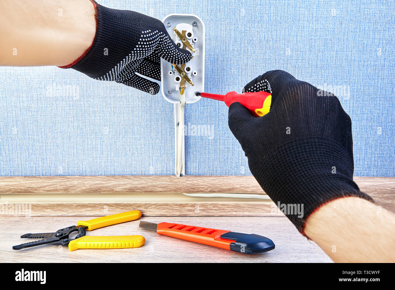 Worker in protective gloves is twisting screw in new electric