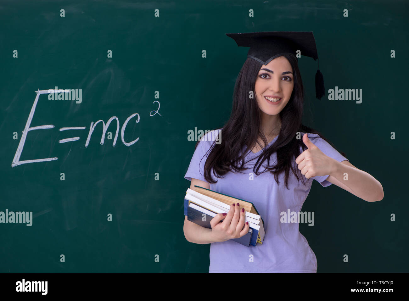 Female graduate student in front of green board Stock Photo - Alamy