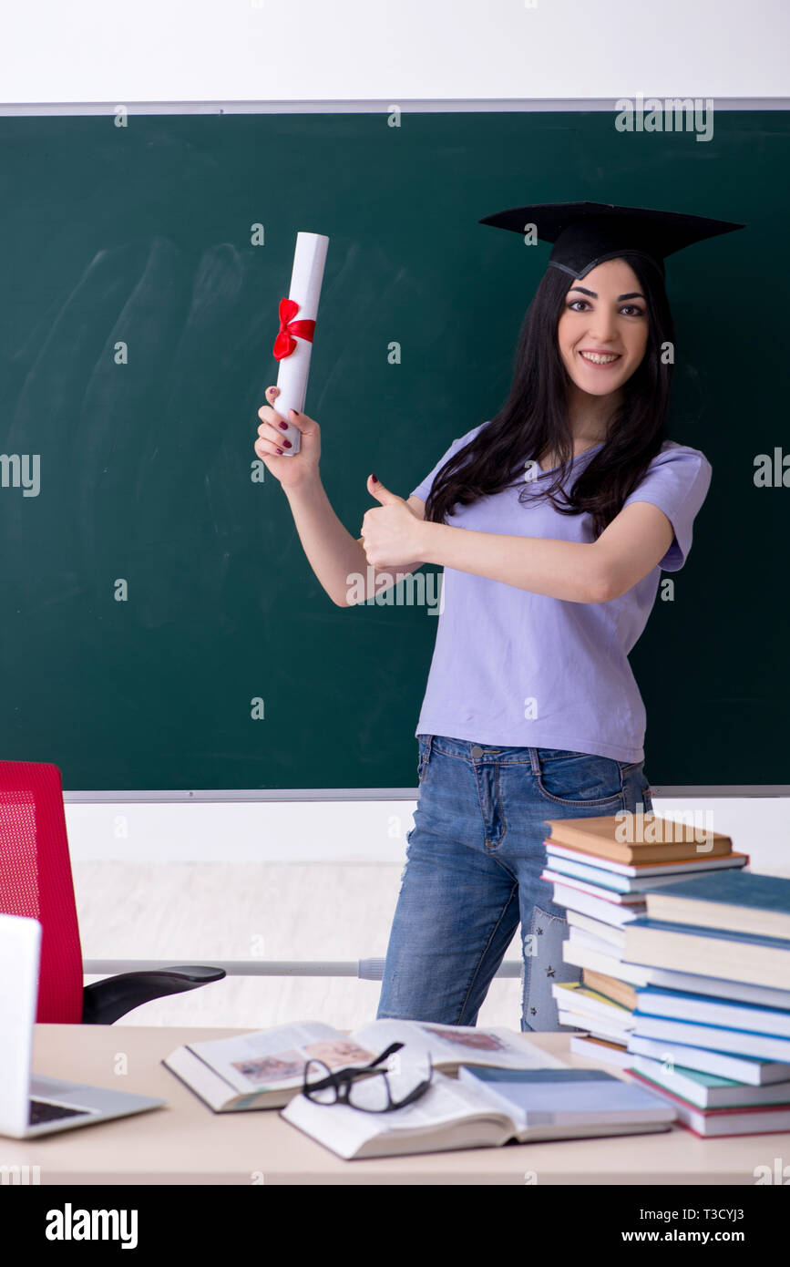 Female graduate student in front of green board Stock Photo - Alamy