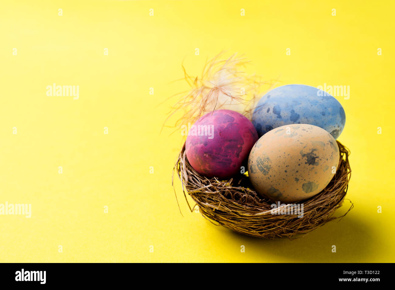 Colorful easter egg in the nest on yellow background with copy space ...