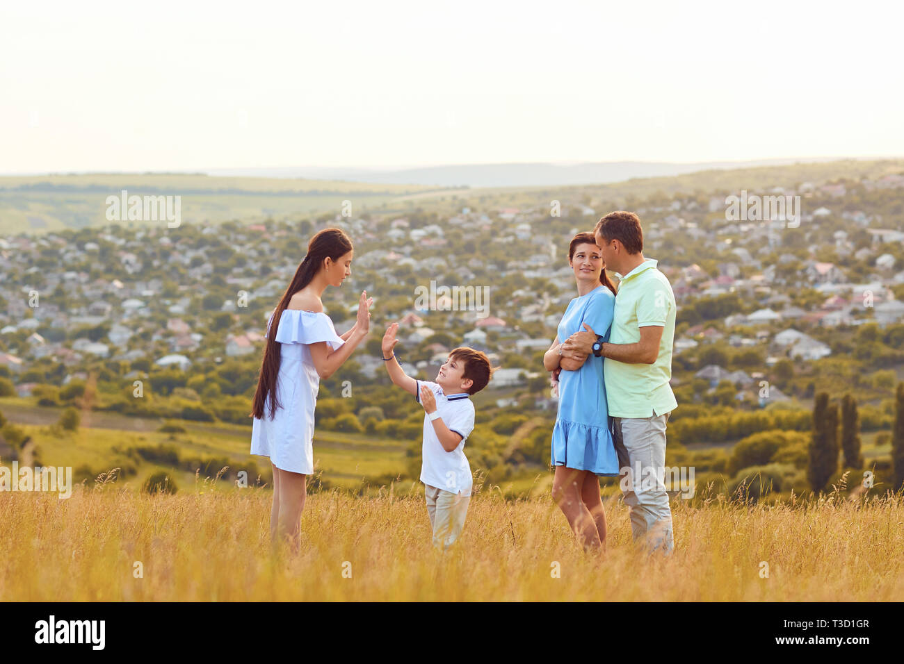 Happy family playing fun on the field at sunset. Stock Photo