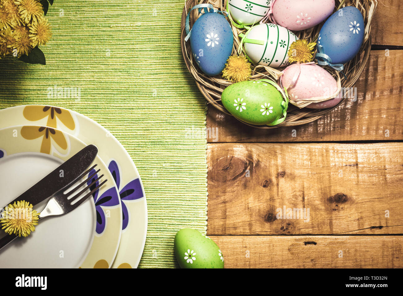 Easter table setting with colorful eggs and spring flowers on wooden ...