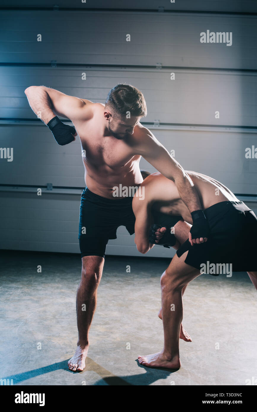 strong muscular shirtless mma fighter punching another while sportsman