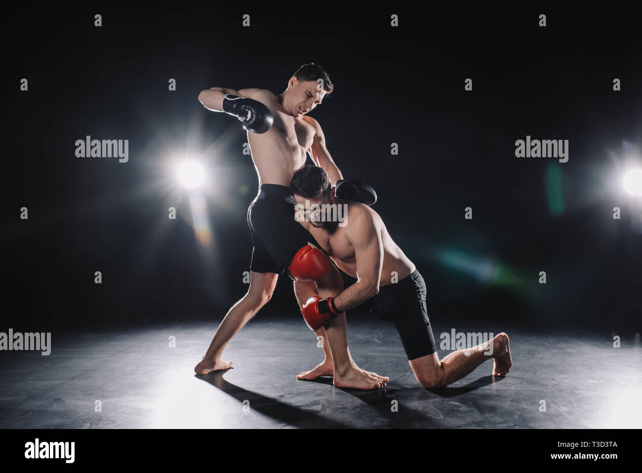 barefoot strong muscular mma fighter in boxing gloves clinching another