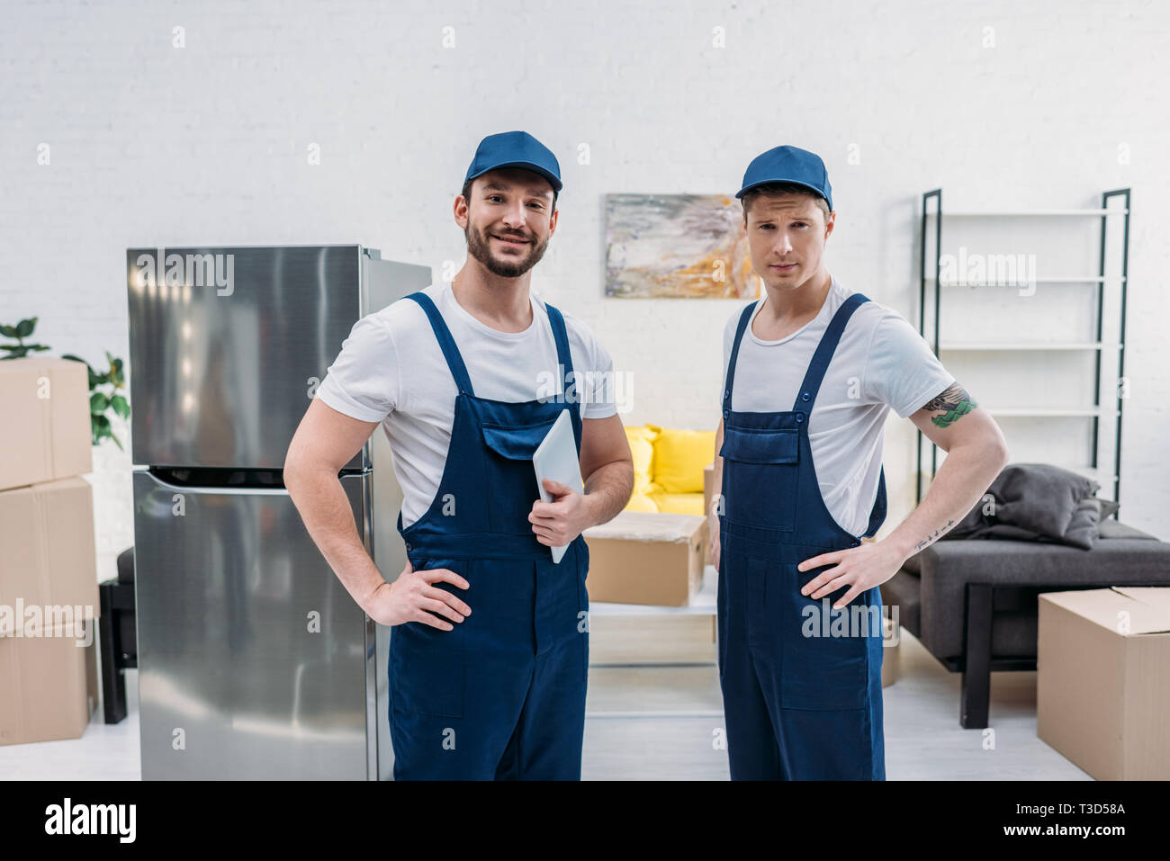 two handsome movers with digital tablet looking at camera in apartment Stock Photo