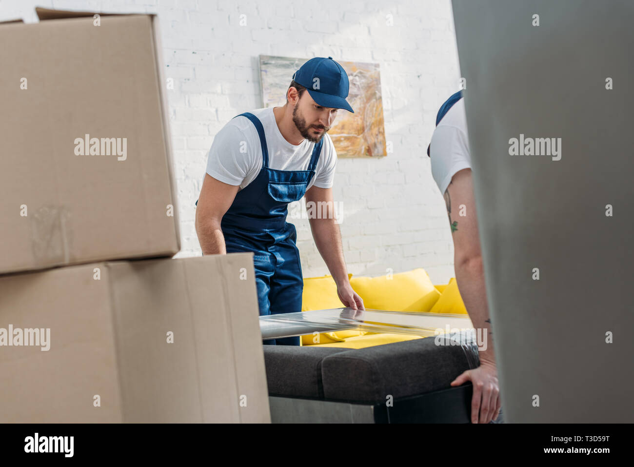 selective focus of movers wrapping furniture with roll of stretch film