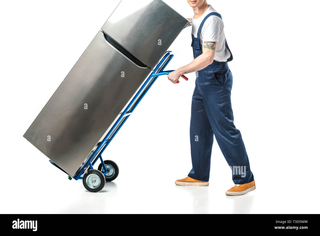 cropped view of mover in uniform transporting refrigerator on hand truck isolated on white Stock Photo