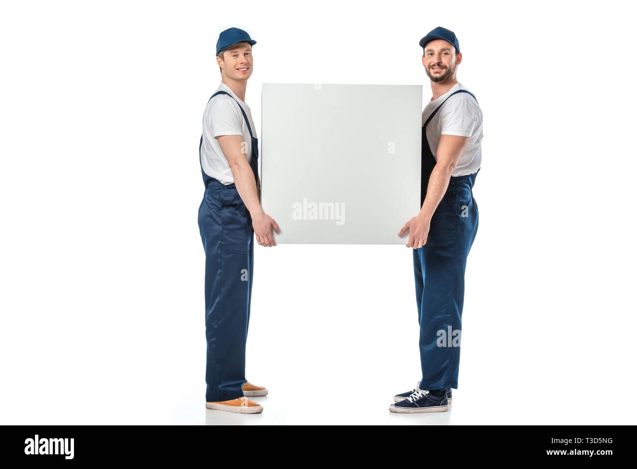 two smiling movers looking at camera while holding blank box isolated on white Stock Photo