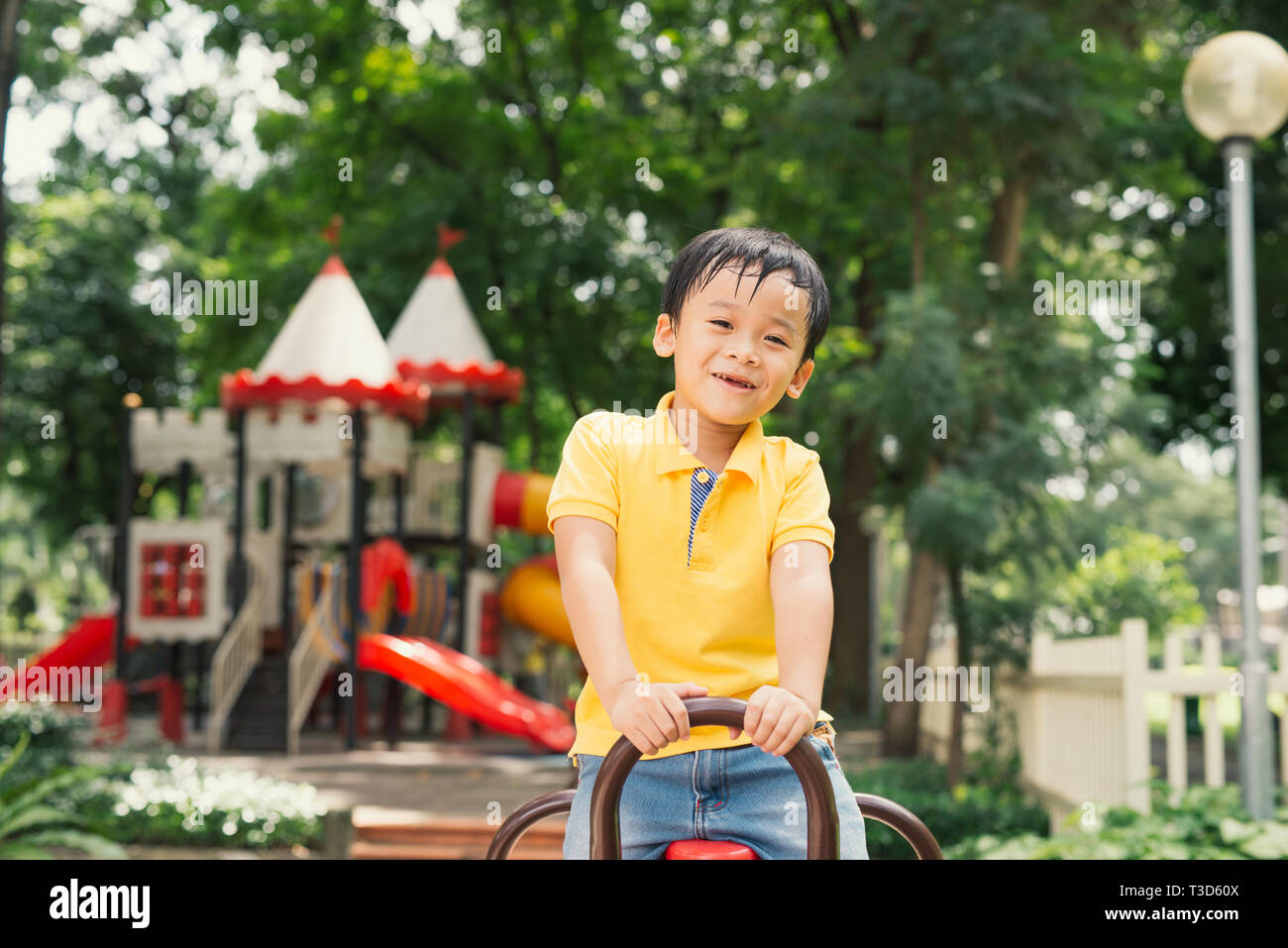 joyful boy in elementary school age riding toy on children's playground Stock Photo