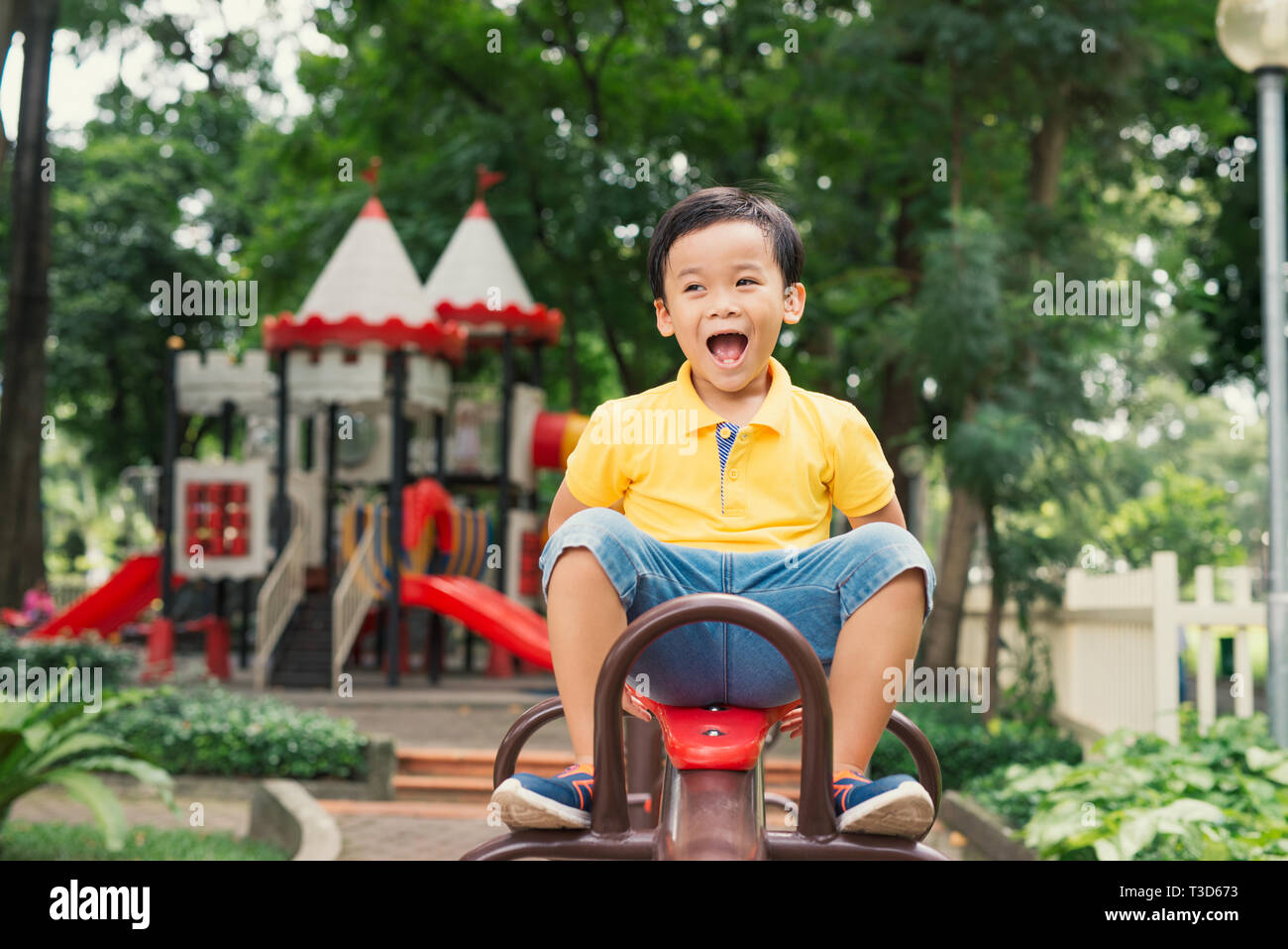 joyful boy in elementary school age riding toy on children's playground Stock Photo