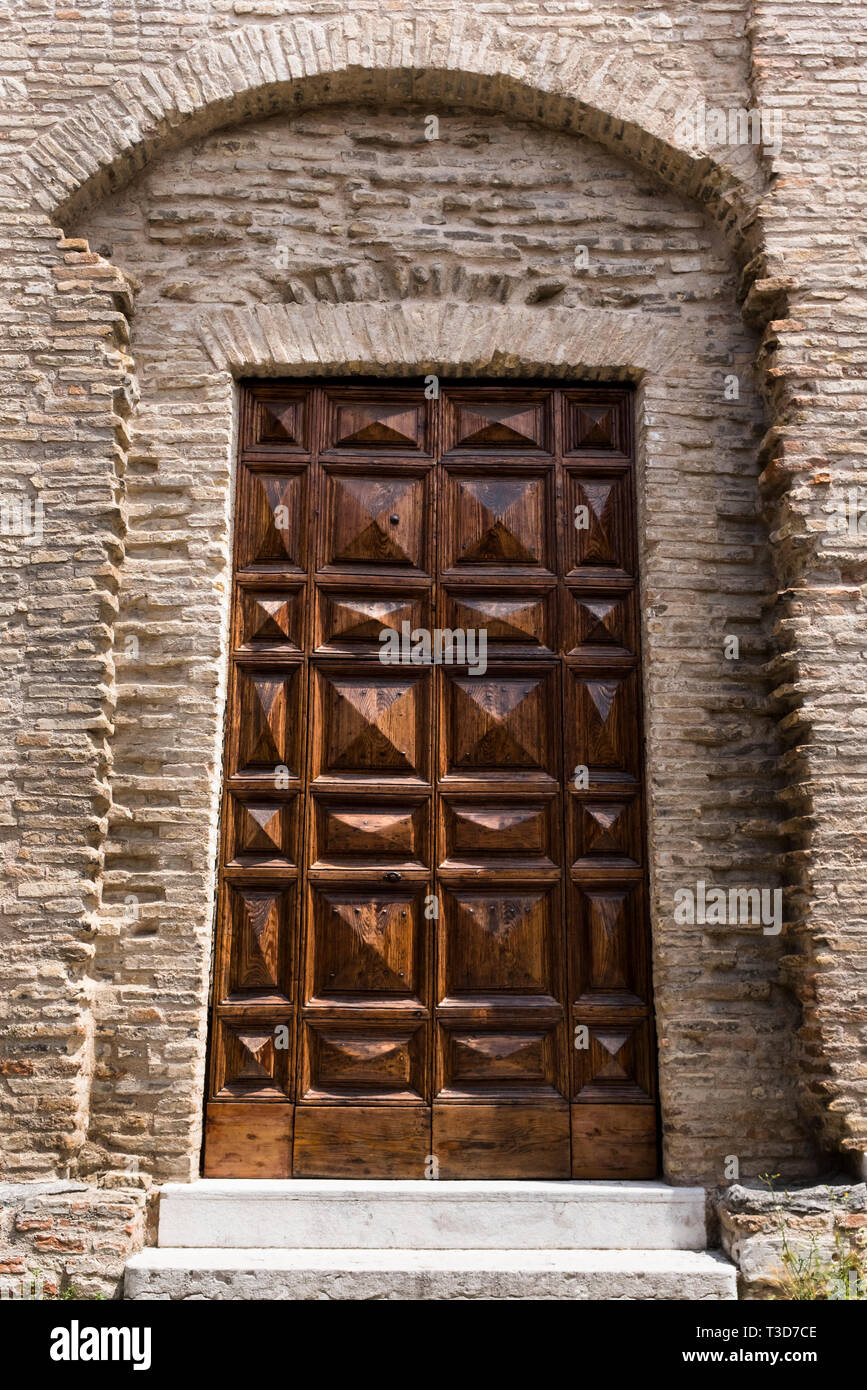 Detail of a large, heavy carved door set in the stone wall of a church ...