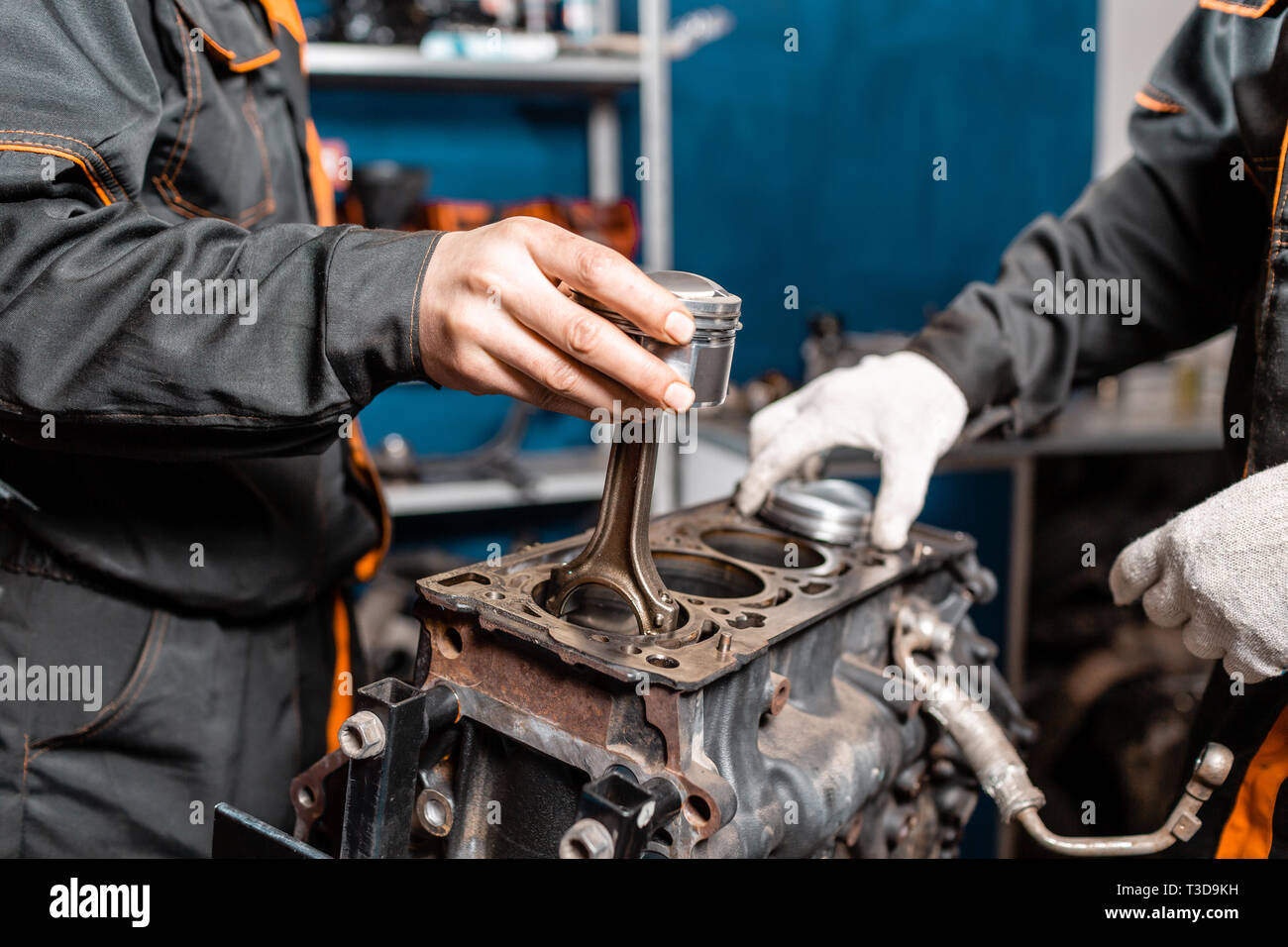Two mechanic holding a new piston for the engine, overhaul.. Engine on a repair stand with
