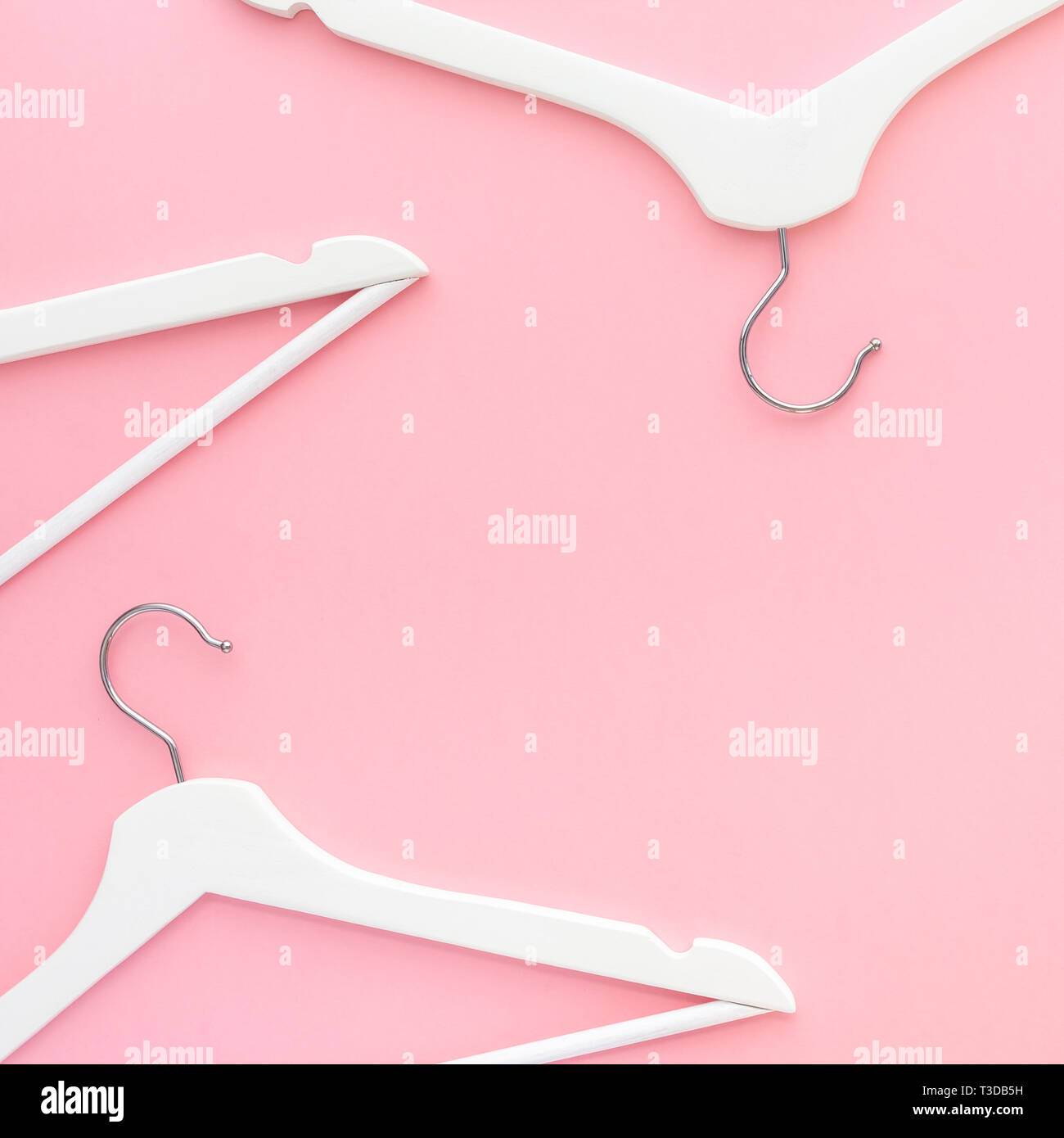 Creative top view flat lay white wooden hangers pastel millennial pink background with copy space minimalism style. Template fashion feminine blog soc Stock Photo