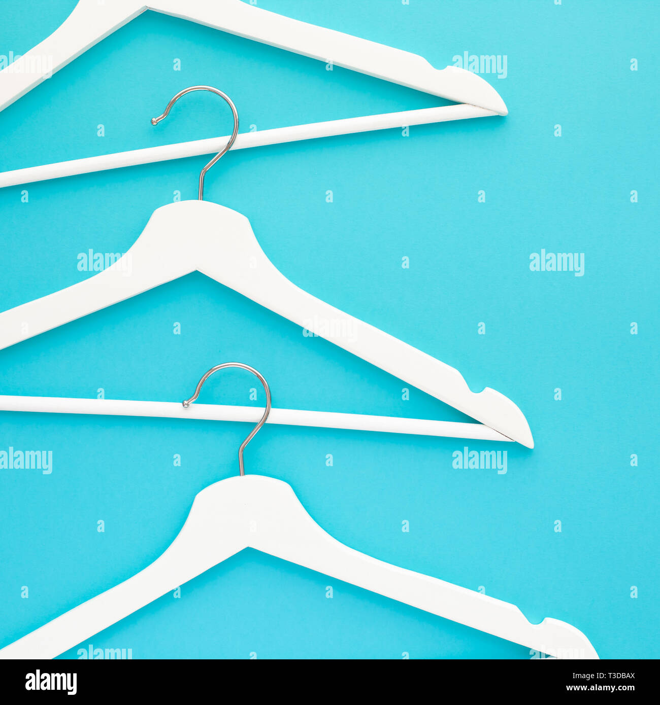 Creative top view flat lay white wooden hangers isolated bold blue turquoise background with copy space minimalism style. Template fashion feminine bl Stock Photo
