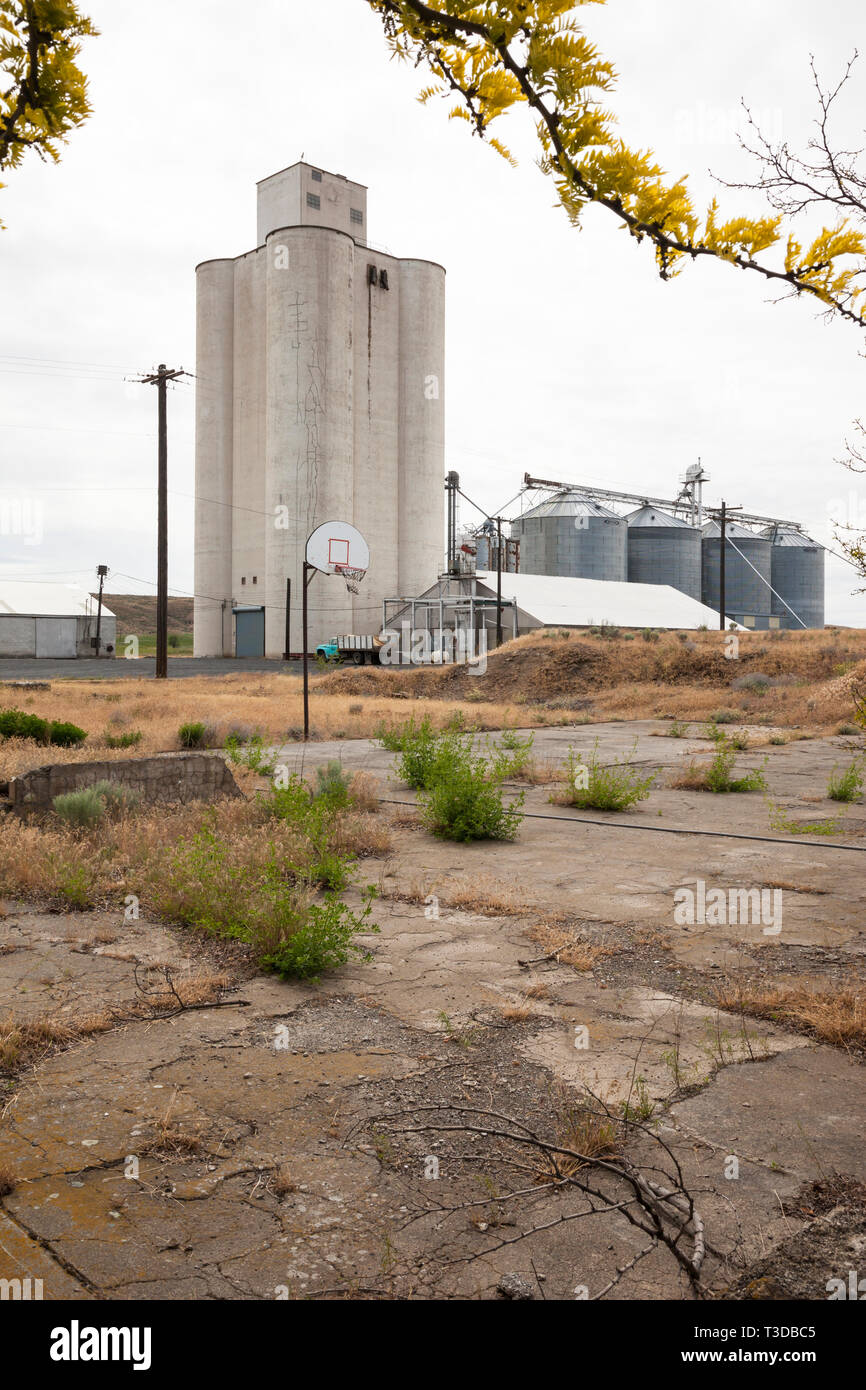 Abandoned basketball court next to grain silos. Poor economy in United States agricultural towns middle America. Stock Photo