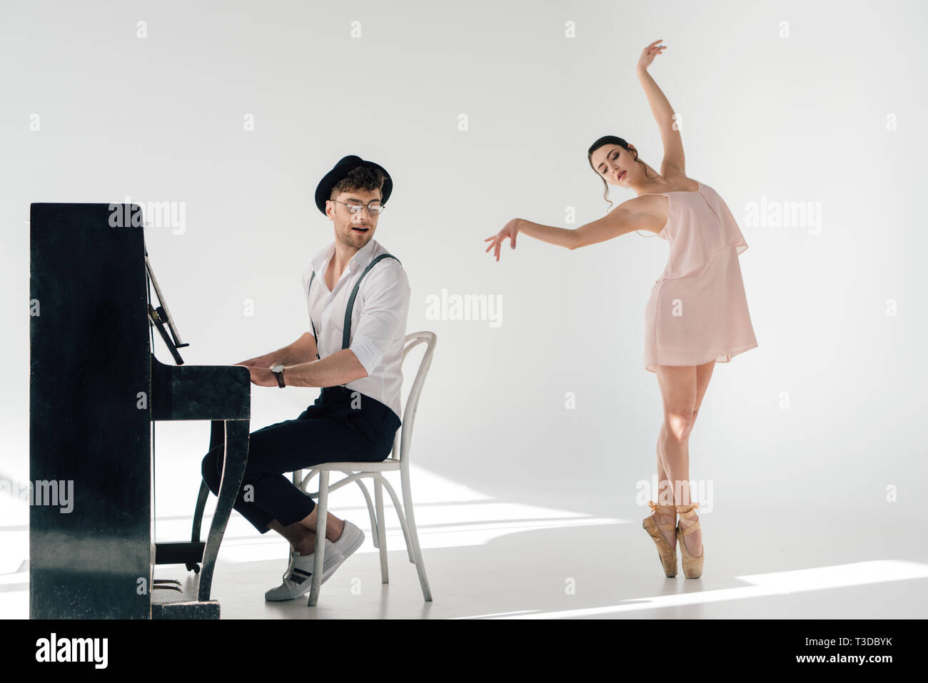 musician playing piano while attractive ballerina dancing near him
