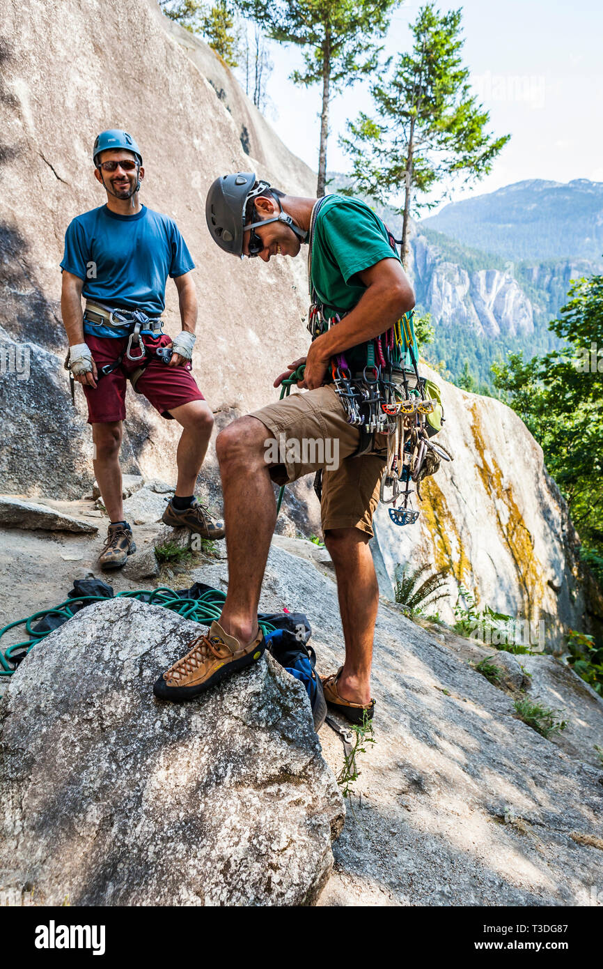 A man tying into a climbing rope while getting ready to lead a rock climb while his partner