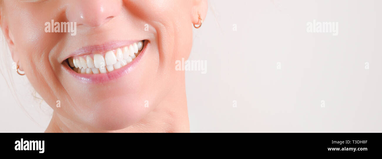 Caucasian mature woman with hoop earrings showing perfect natural white teeth in front Stock Photo