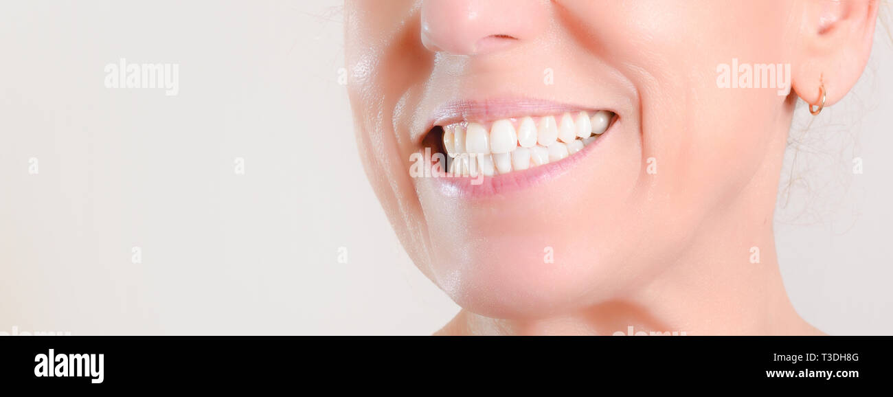 Caucasian mature woman with hoop earrings showing perfect natural white teeth on the side Stock Photo