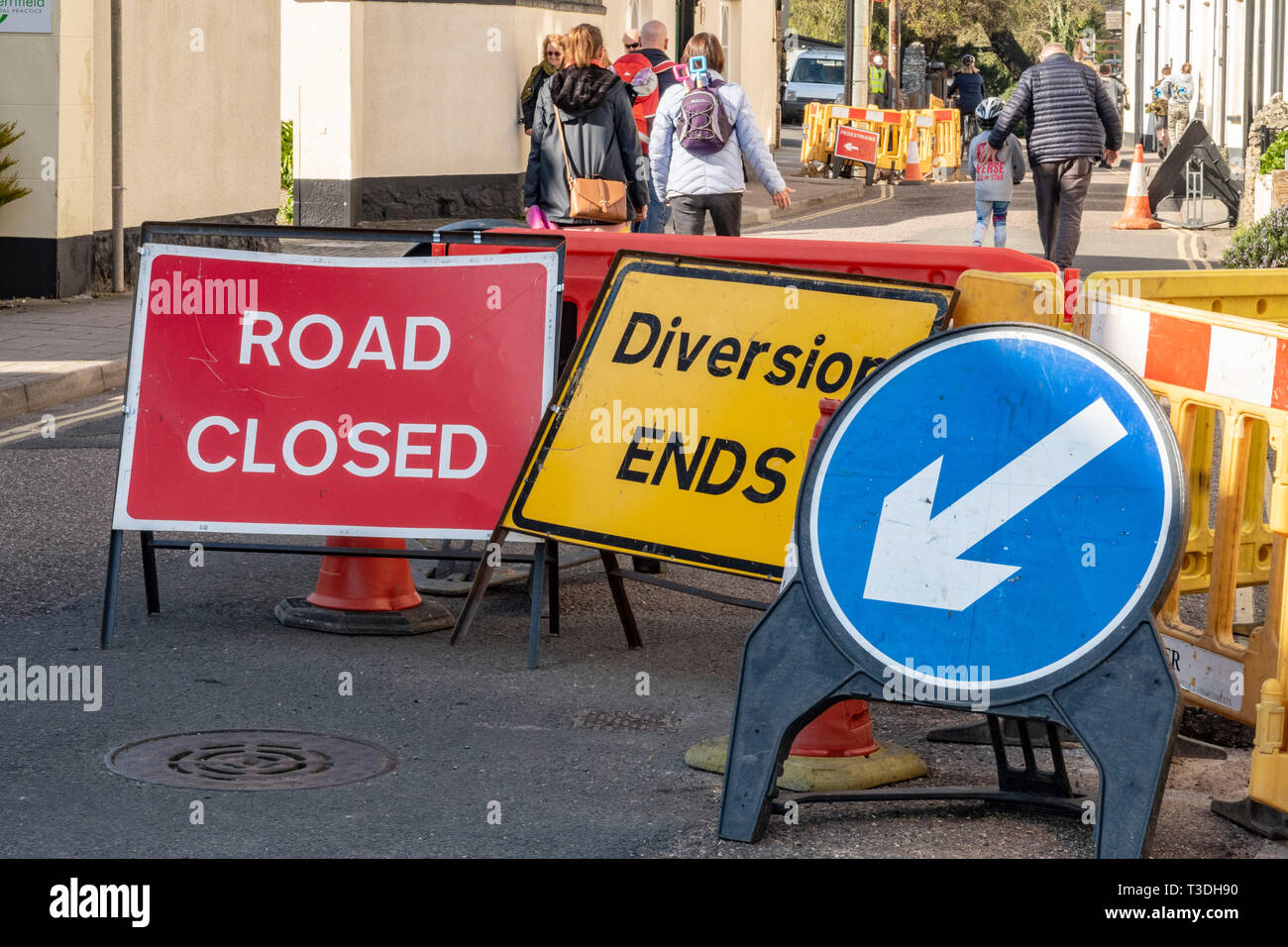 People walking past a road closure. Road closed, Diversion, ends, keep left signs and notices, Sidmouth, Devon, UK Stock Photo