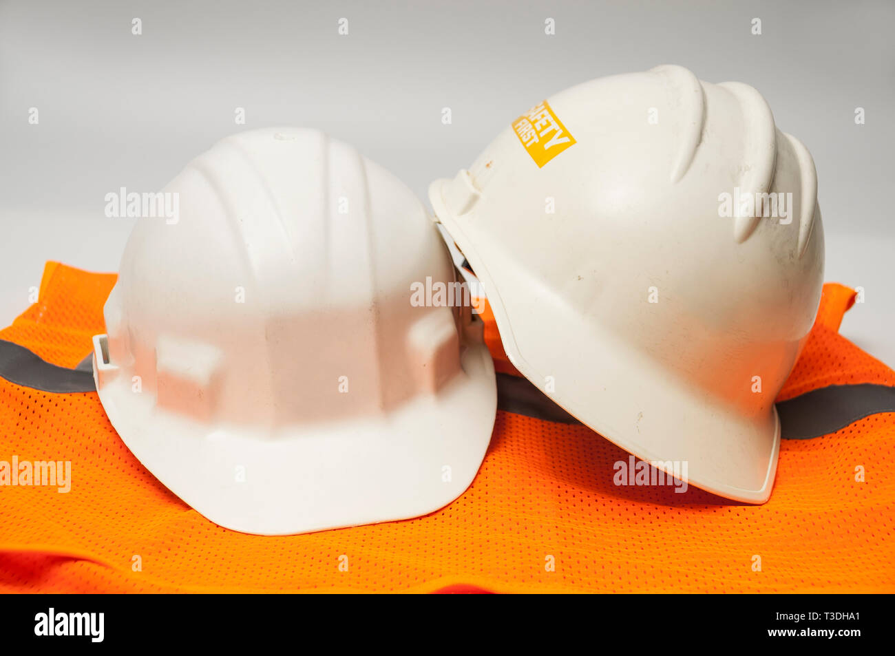 Two used hard hats and an orange vest Stock Photo - Alamy
