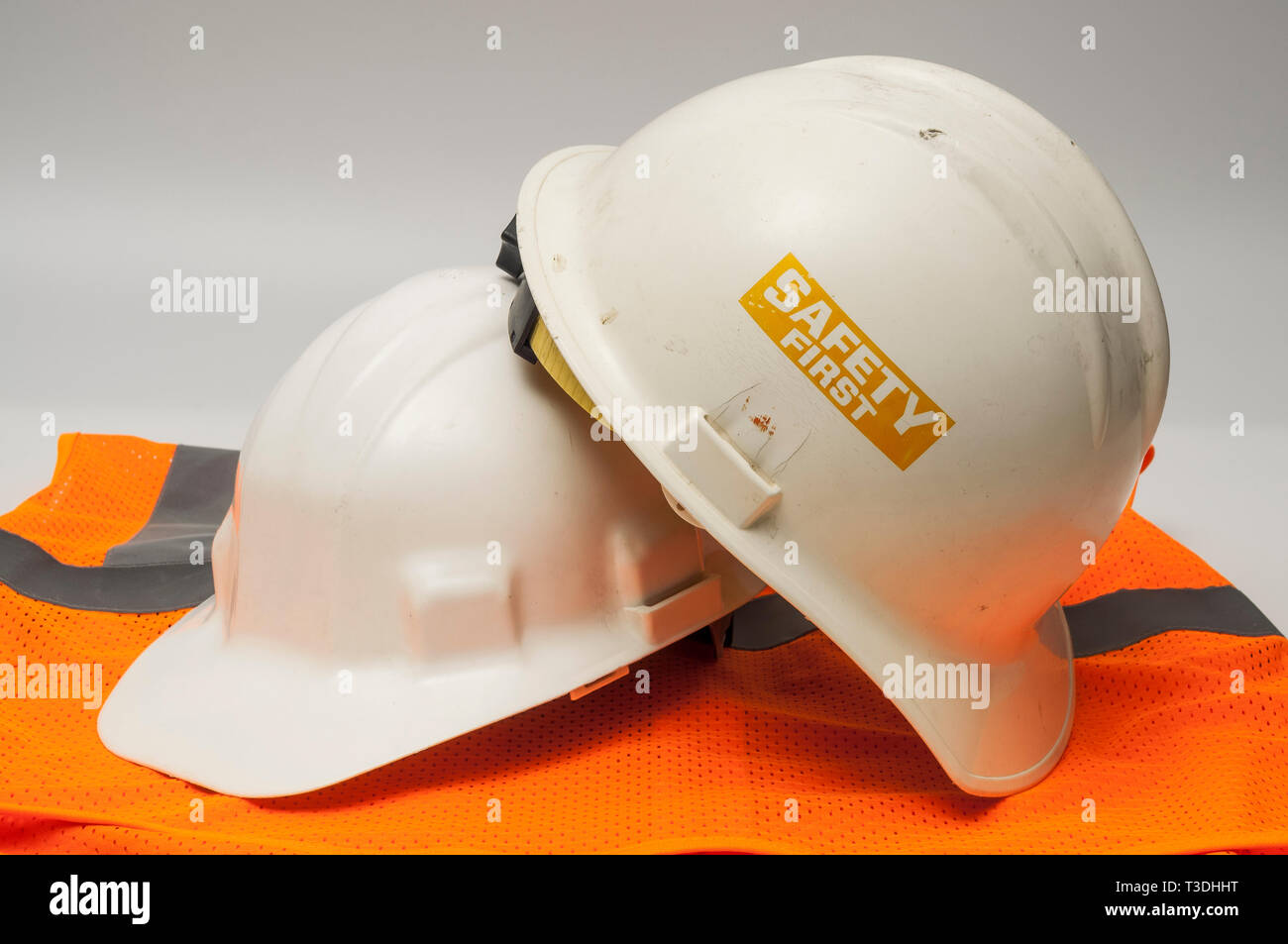 Two used hard hats and an orange vest Stock Photo Alamy