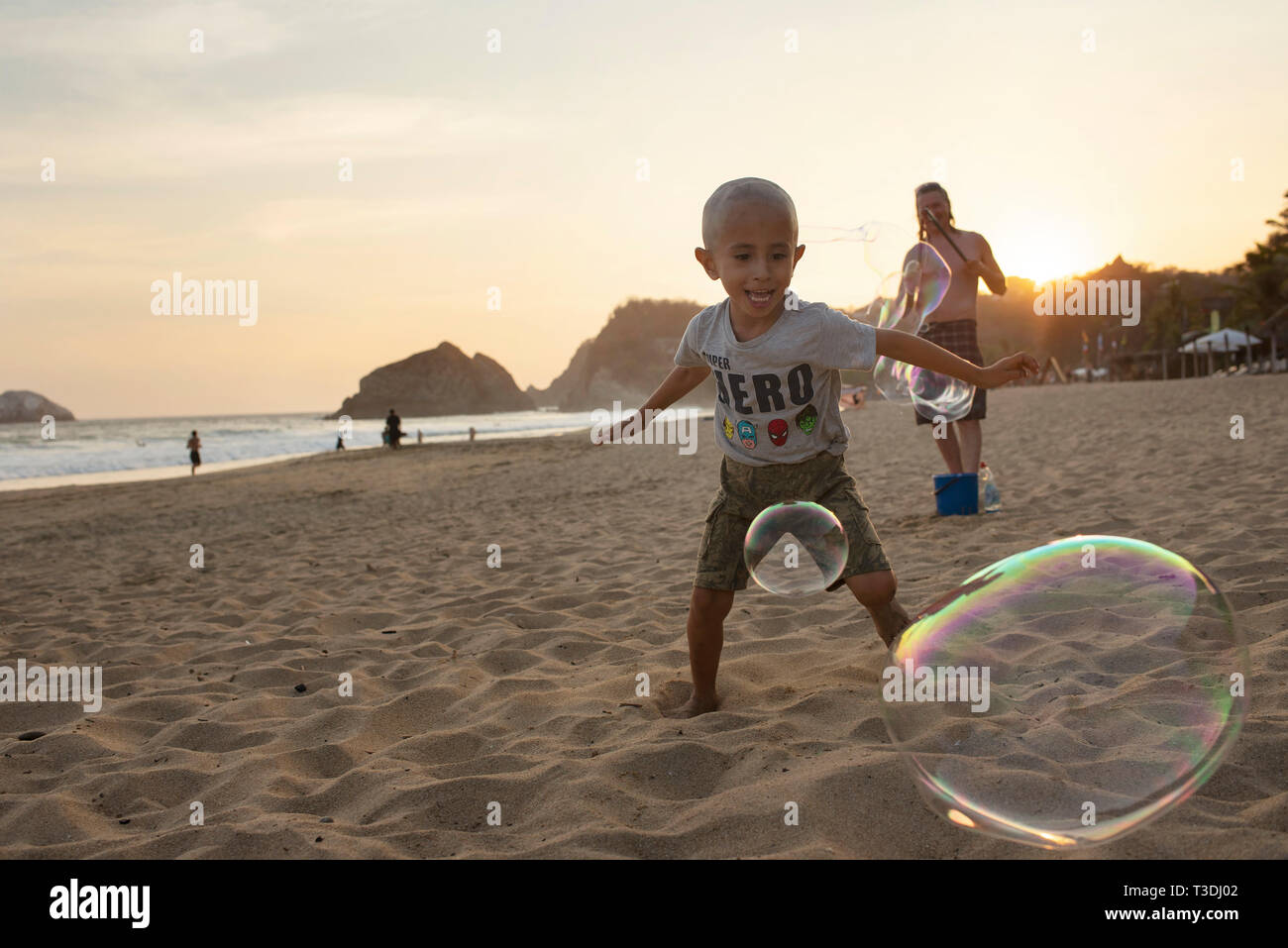 Local boy chasing bubbles. Zipolite Beach, Oaxaca State, Mexico. Apr 2019 Stock Photo