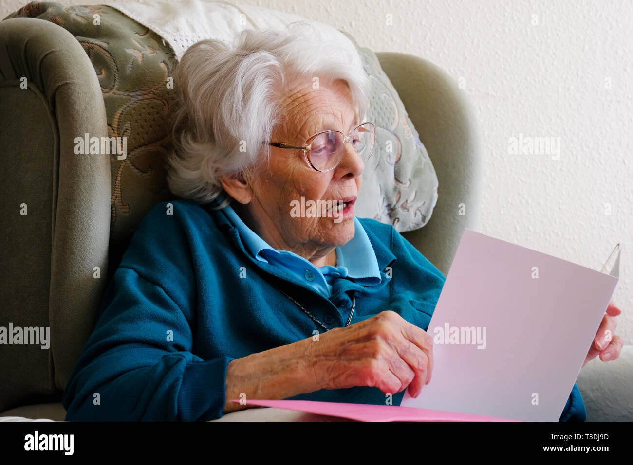 Real life image of an elderly woman reading a greetings card - John Gollop Stock Photo