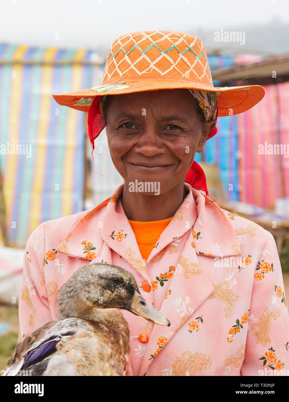 Portrait of Malagasy woman with traditional straw hat and holding a duck at a farmers market,hill country,Madagascar,Africa Stock Photo