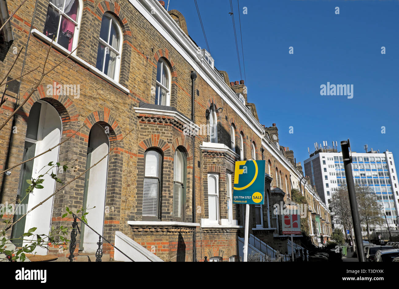 Foxton house for sale sign outside row of terraced houses housing and blue sky copy space in street in Brixton South London England UK  KATHY DE WITT Stock Photo