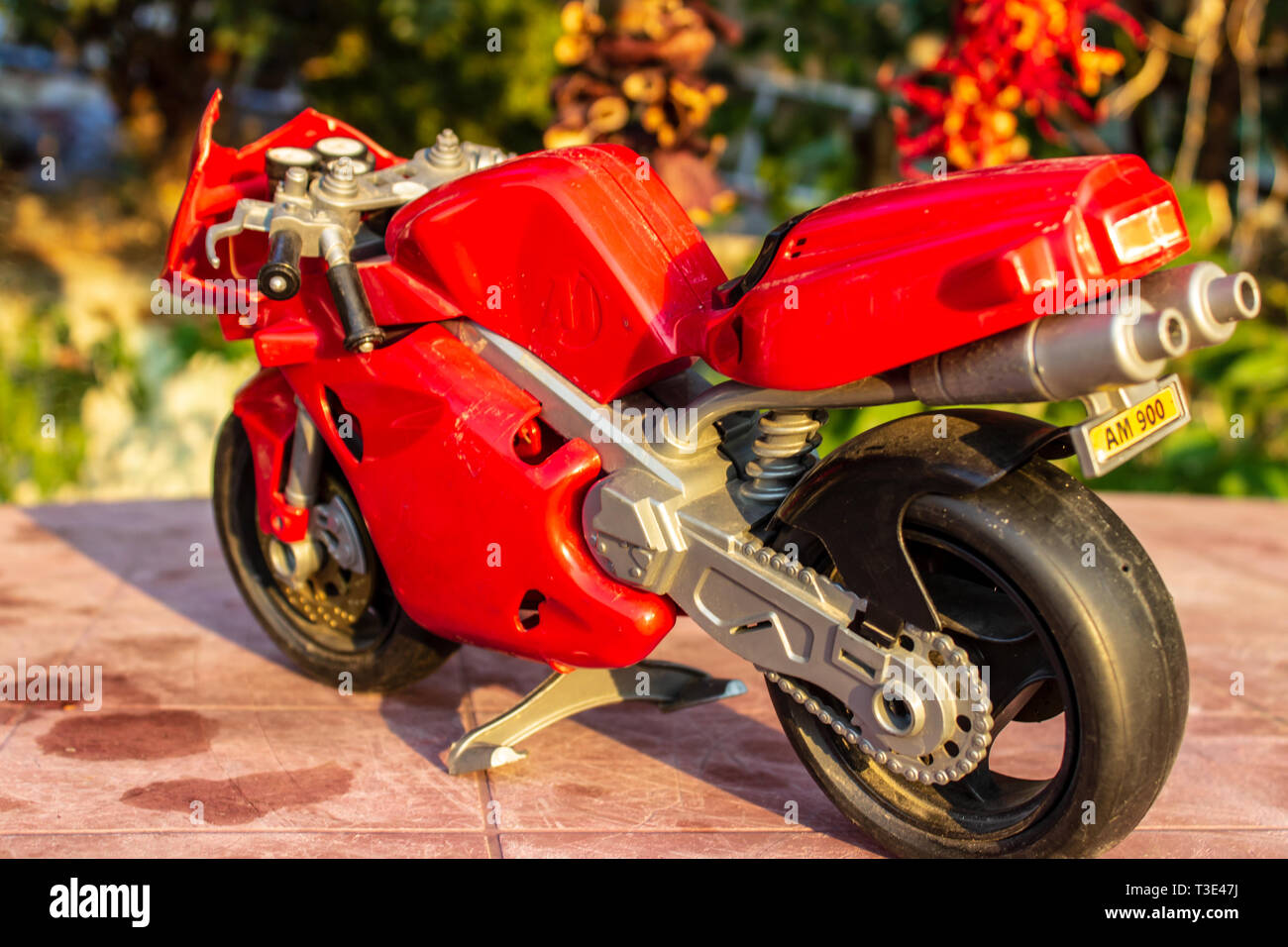 a isolated closeup red toy motorcycle with warm colors. photo has taken from a garden. Stock Photo