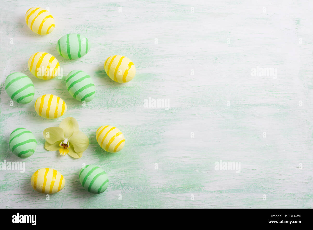 Easter background with green striped painted eggs and yellow orchid. Happy Easter greeting card, copy space. Stock Photo