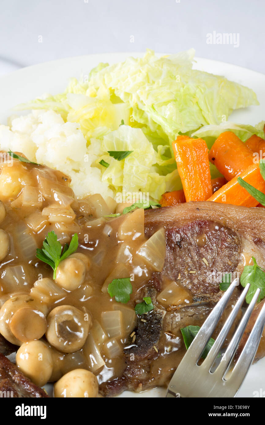 An English meal of Barnsley chop and Mushroom reduction served with Creamed Potato, glazed Carrot and Savoy cabbage. Stock Photo