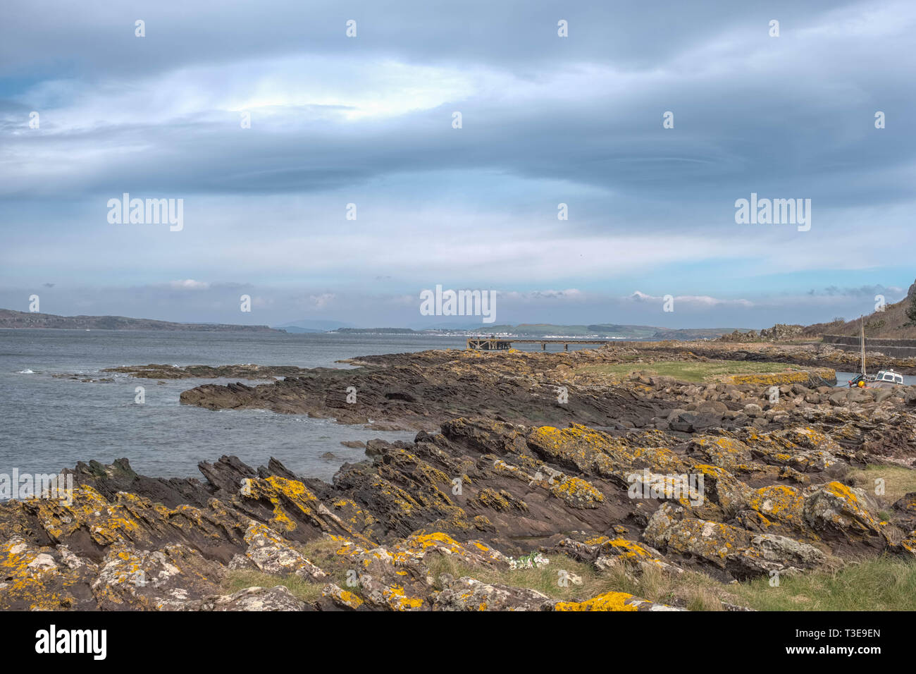 Looking over the rocky harbour  to the old jetty at Portencross in Seamill West Kilbride on a cold bright day in Scotland. Stock Photo