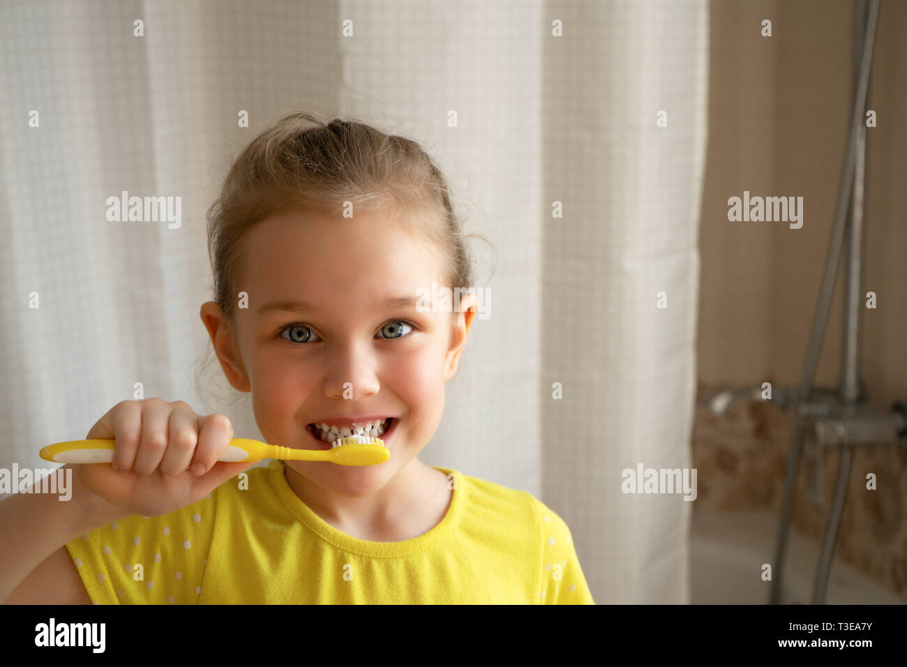 Little cute blond girl brushes her teeth with a toothbrush in the