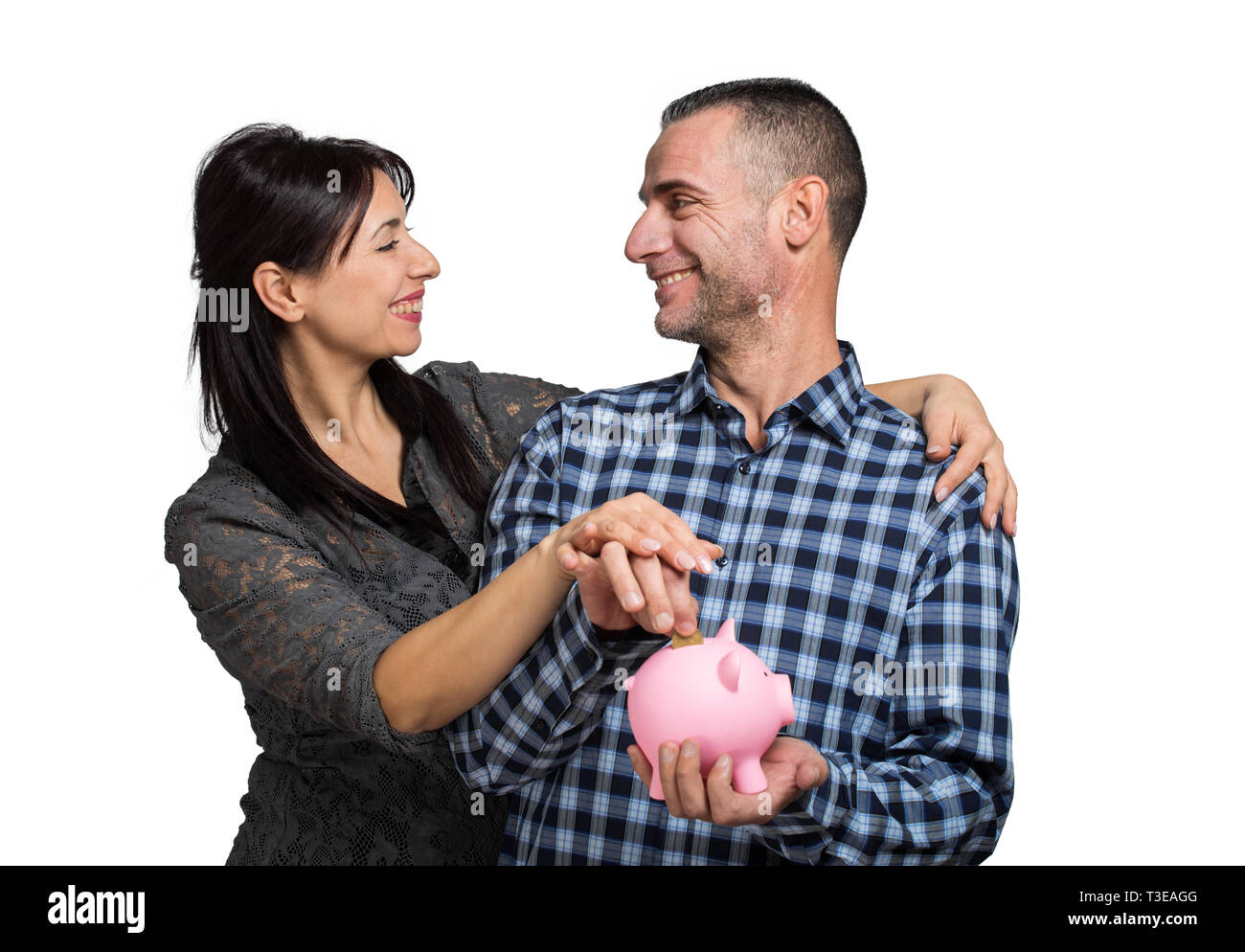 Happy couple inserting a coin into a piggy bank Stock Photo - Alamy