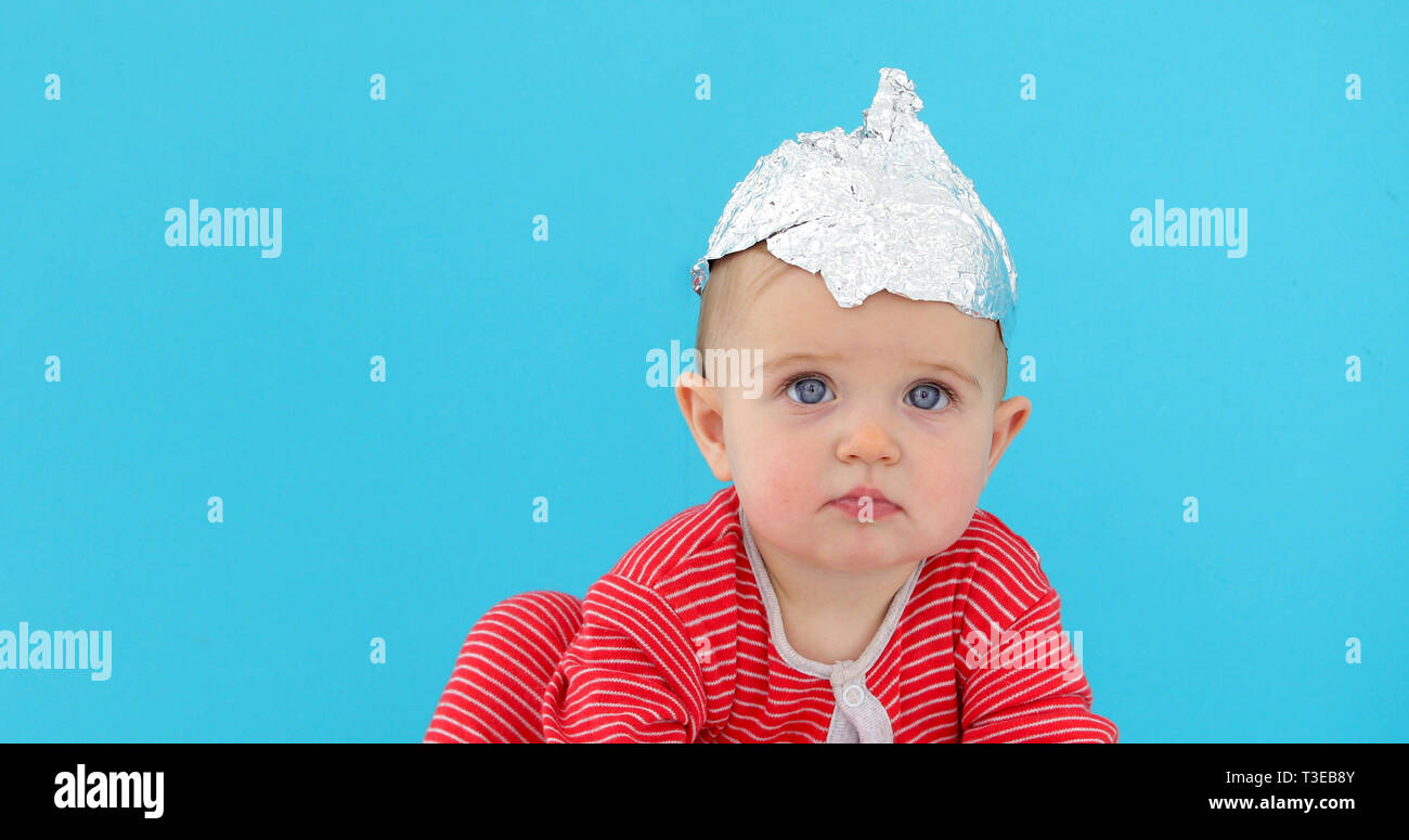 https://c8.alamy.com/comp/T3EB8Y/baby-in-a-foil-hat-sits-on-a-blue-background-T3EB8Y.jpg
