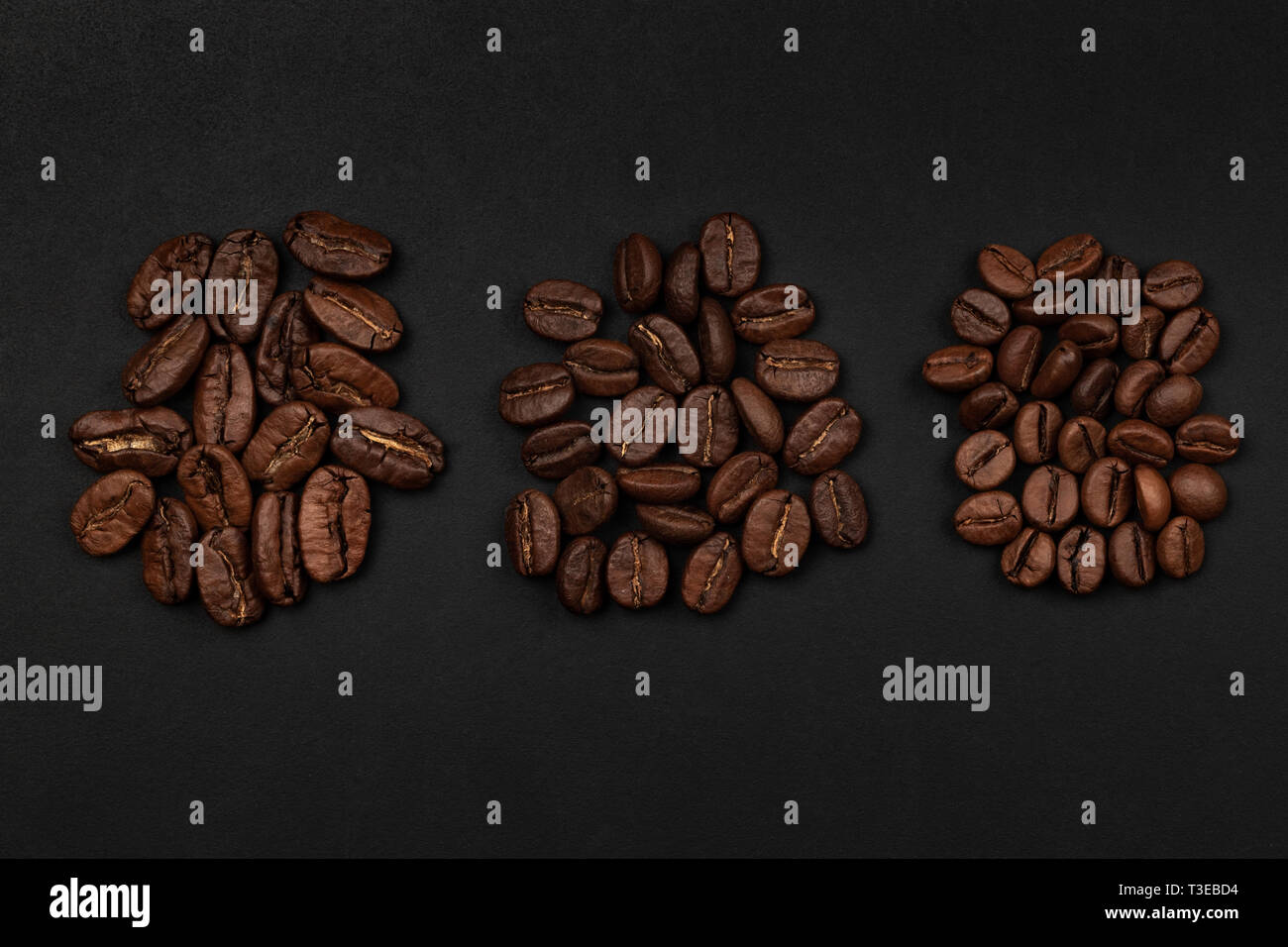 Roasted coffee beans piles from top on black background Stock Photo - Alamy