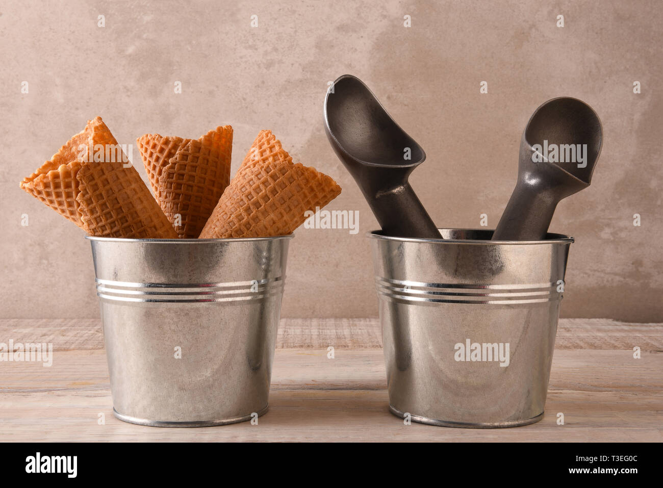 Closeup of three ice cream cones in a small metal bucket next to a pail with two scoops. Stock Photo