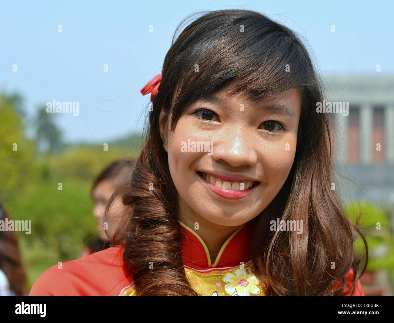 Vietnamese girl with curls wears the traditional Vietnamese silk dress (áo dài) and poses for the camera. Stock Photo