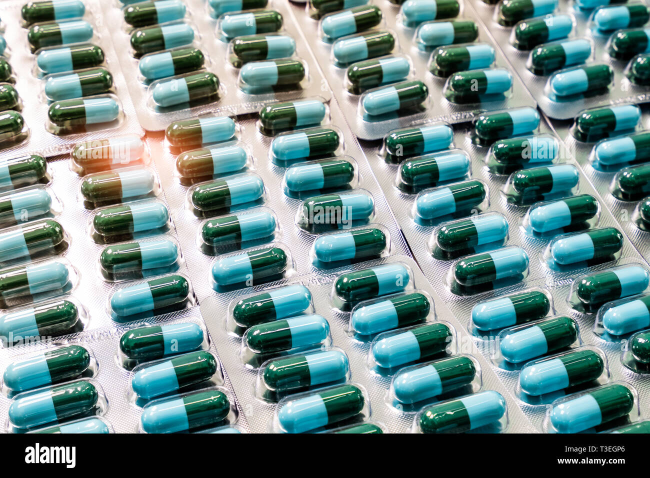 Closeup green-blue antibiotic capsule pills in blister pack. Antimicrobial drug resistance. Pharmaceutical industry. Global healthcare. Pharmacy Stock Photo